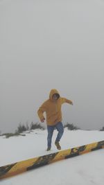 Full length of girl standing on snow covered landscape against clear sky