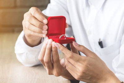 Close-up of couple holding wedding ring at table