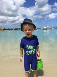 Cute boy on beach against sky