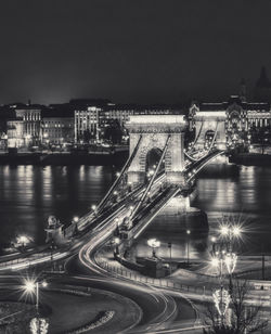 Illuminated bridge over river in city at night