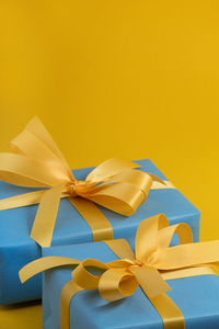 Blue gift boxes with yellow ribbons on a yellow background. space for your text.