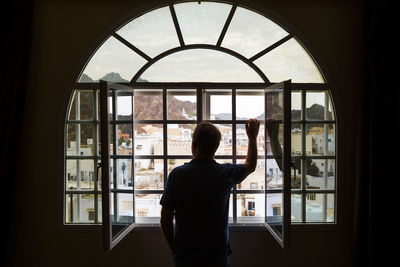 Man standing looking out of open window, mutrah, oman