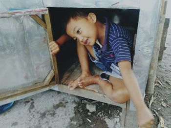 Playful boy sitting in abandoned cabinet