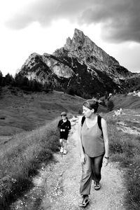 Rear view of people walking on mountain against sky
