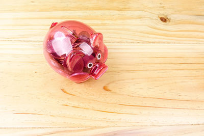 High angle view of coins in piggy bank over table