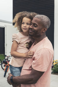 Man carrying daughter with woman and son in front yard