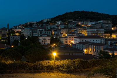 Illuminated city against clear blue sky at night