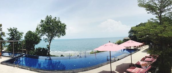 Panoramic view of swimming pool by sea against sky