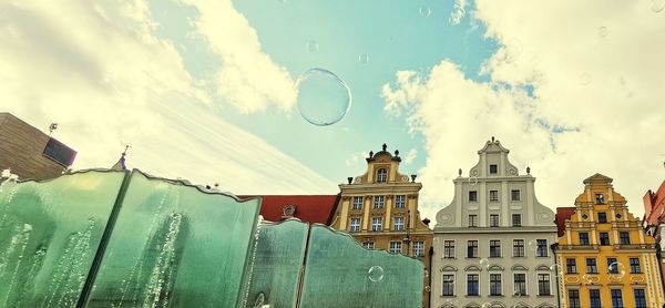 Low angle view of buildings against cloudy sky