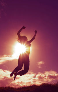 Silhouette of woman jumping against sky