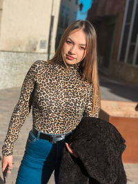 Portrait of beautiful young woman with long hair standing outdoors