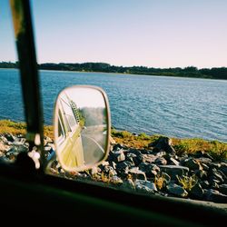 Reflection of van on side-view mirror against sea