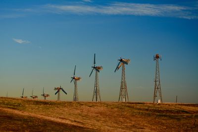 Wind turbines on field against blue sky