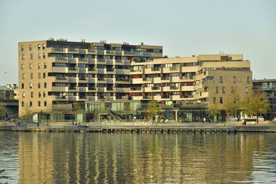 Buildings by river against sky in city