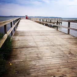 Wooden pier on beach against sky
