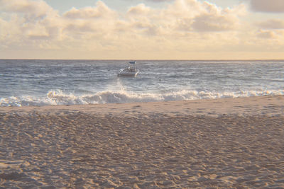 View of calm beach against cloudy sky