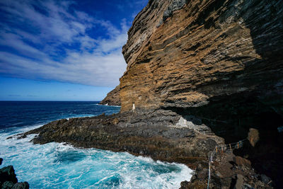 Rock formation on sea shore against sky