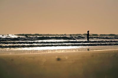 Silhouette man standing on beach against clear sky