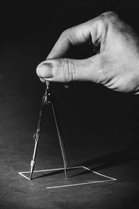 Close-up of person holding paper against black background