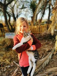 Portrait of girl holding cat while standing on land