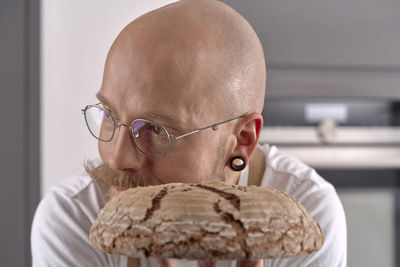 Man holding fresh sourdough bread in front of his face