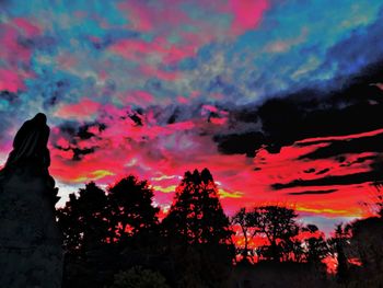 Low angle view of silhouette trees against dramatic sky