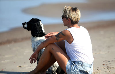 Rear view of woman with dog sitting on beach