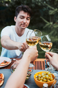 Friends making toast during summer picnic outdoor dinner in a home garden