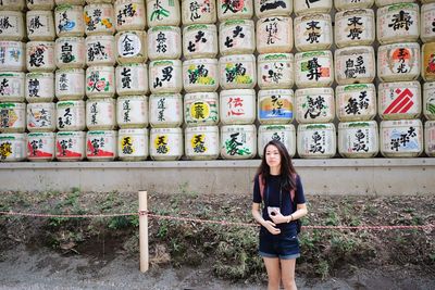 Portrait of smiling young woman standing against wall