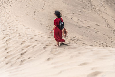 Rear view of woman walking on sand at beach