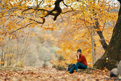 Full length of man sitting on road during autumn