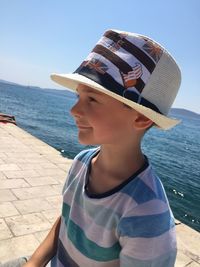 Boy wearing hat against sea against sky