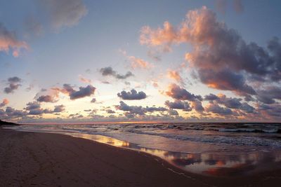 Scenic view of beach against sky at sunset