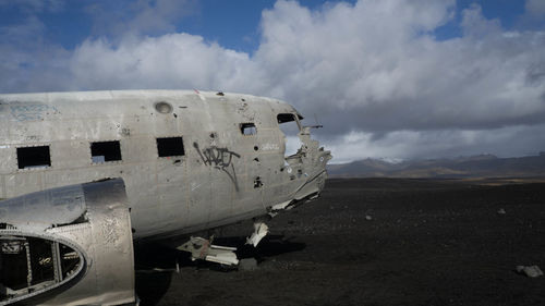 View of abandoned airplane against cloudy sky