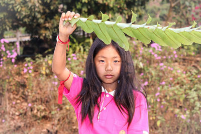 Portrait of young woman holding plant outdoors