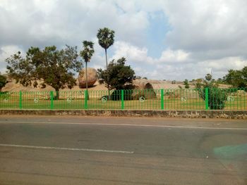 Road by trees against sky