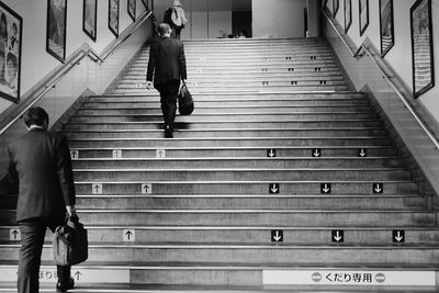 Rear view of people walking on staircase