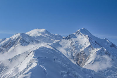 Scenic view of snowcapped mountains against clear blue sky