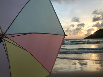 Sunset on beach with pastel colorful umbrella and beautiful sunlight shines on peaceful wave