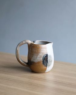 Small handmade pitcher jug on wooden table