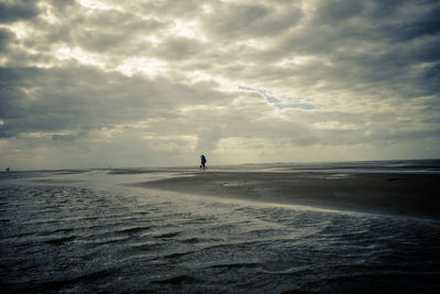 Silhouette of man standing on beach against sky