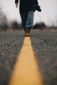 Low angle view of woman walking along yellow line on road.