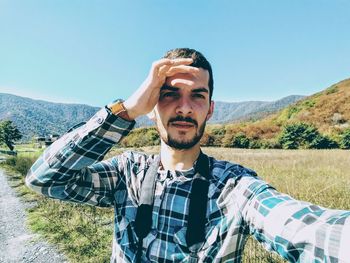 Portrait of young man taking selfie against clear blue sky during sunny day