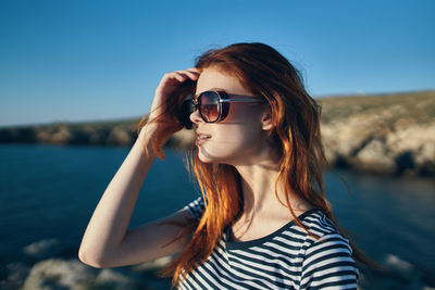 Portrait of young woman wearing sunglasses against sky