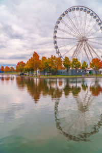 Ferris wheel by lake against sky