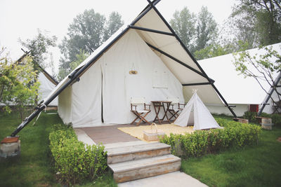 Tent on field by house against sky