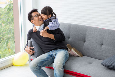 Playful father and daughter on gray sofa at home