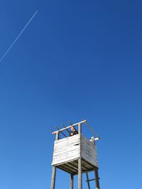 Low angle view of woman standing in lookout tower against sky