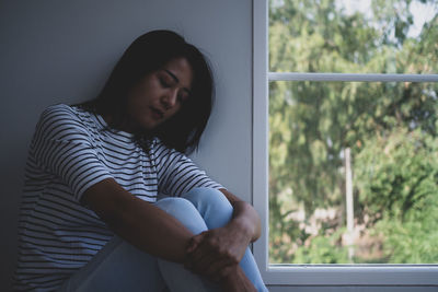 Young woman looking through window