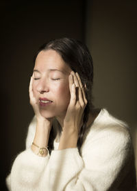 Portrait of young woman against black background